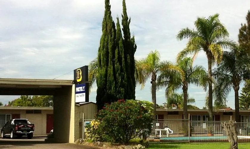 The single-storey court at Mayfield Motel — a long row of red doors under a continuous awning, with the pool beyond.