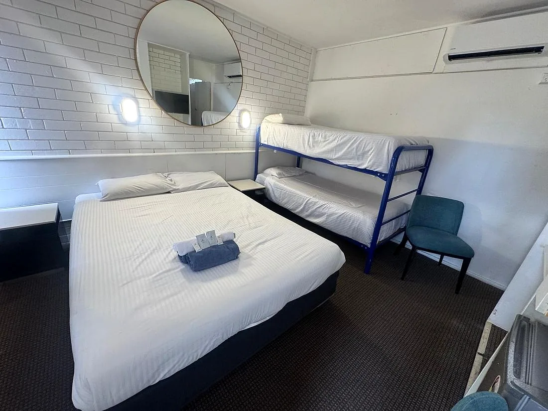 Refurbished Family Room at Mayfield Motel — double bed and a bunk bed, painted white brick, round mirror, wall sconces and split-system air conditioning.