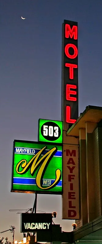 Mayfield Motel’s original 1962 pylon sign lit at dusk — vertical red neon reading MOTEL, a green 503 disc, the Mayfield script panel, and a lit VACANCY sign below.